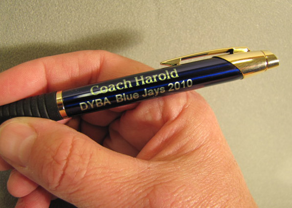 Image of blue color ballpoint pen engraved with the coaches name and the team name 